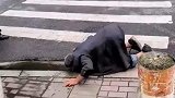 老人趴在路边喝地上的积水
