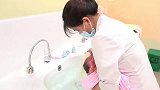 护士给新生儿宝宝洗澡，宝宝享受着并不时地斜眼看护士几眼