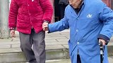 老人扶老伴下台阶，随后老伴牵着老人的手离开
