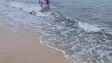 女子带小孩海边玩，怕小孩被浪打用身体挡