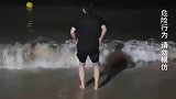 男子夜晚在海边跳海浪没想到大浪袭来，吓得使劲逃跑