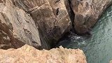 一男子踩着悬崖峭壁钓鱼