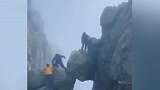 多名游客攀爬泰山仙人桥景点巨石，巨石相互抵撑下方悬空