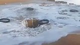 男子将轮胎丢进深坑中，任由海浪冲上天