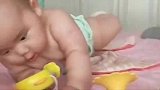 小宝宝趴在床上玩，手里还拿着妈妈新买的玩具，小表情太萌了！