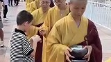 僧人们排队，等待小男孩布施