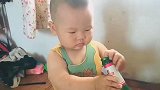 宝宝拿着爸爸喝完的啤酒瓶，放嘴里唆，像个小男子汉