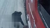 雪天路滑，大货车上坡困难，好心人拔草相助帮司机脱困。