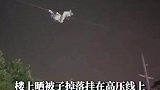 楼上晒被子掉落挂在高压线上，电力工作人员攀爬作业