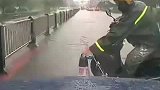 一车辆雨中行驶，遇前方漂来的路障，路过的外卖小哥帮忙拿开