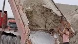 车后斗的沙土凝结，男子用铁锹一点点铲下
