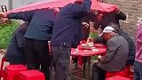 喜宴上突然降雨，众人举起餐布当伞，继续干饭