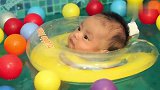 宝宝戴着游泳圈在水里游泳，太好玩了，可爱