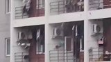 女生在宿舍拍男寝阳台救灾现状，男生们打伞拿盆卖力往楼下舀水