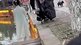 男生蹲地上给女孩拍照，用前置摄像头，女孩自己选角度