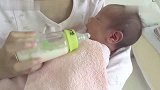 妈妈给两周大的婴儿奶瓶喂奶，宝宝深情的望着妈妈，嘴角都淌奶了