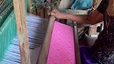 老奶奶用纺织机织布，布料上的纹路逐渐显现