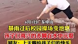 暴雨过后操场变池塘孩子们赤脚在水中玩耍