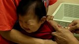 6个月的宝宝攥着小拳头瞪着眼睛望着打针的医生，好可爱！
