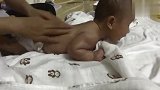 高级月嫂给小宝宝背部做按摩，小宝宝趴在那抬头的模样可爱极了