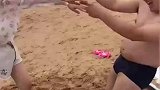 男子和老婆去海边旅游，在沙滩里玩不倒翁