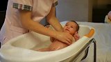 护士阿姨给新生儿洗澡，宝宝不哭也不闹，乖乖的样子真可爱！