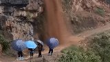 崖边山洪倾泻阻断交通，四小孩淡定撑伞驻足观看 目击者急坏了