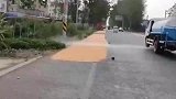 洒水车上路作业，将路边的稻谷冲毁
