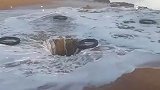 男子将轮胎丢进深坑中，任由海浪冲上天