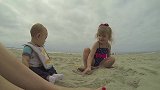女孩子和弟弟一起坐在沙滩上，一起堆小城堡，很是开心呀！