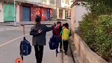 奶奶送俩孙子上学，一边用扁担挑书包，一边挥舞鞭子“赶路