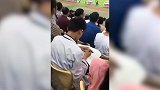 国足场上和泰国踢得火热 这位小哥却在场边淡定写作业