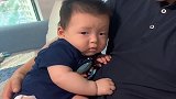 萌娃被叔叔抱着，吓得一动不动，小眼神不停暗示妈妈真逗！