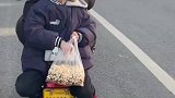 电动车上小男孩吃爆米花，等红绿灯的时候还分给后车人吃