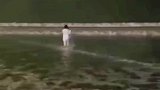 妈妈呼喊着孩子名字，不顾涨潮向海里走去，工作人员一遍遍劝阻