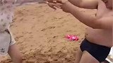 男子和老婆去海边旅游，在沙滩里玩不倒翁