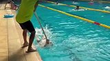 教练利用杆子辅助小学员学习蝶泳