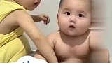 弟弟蹲在澡盆里，姐姐拿着纸巾贴心地给弟弟洗澡