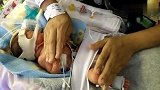 早产儿在保温箱里感觉很不安，妈妈用手安抚宝宝让他有点安全感