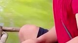 男子铲起一勺鱼料，放入鲶鱼的嘴里