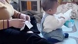 小宝宝前面玩抽纸，奶奶在后面一张一张叠好