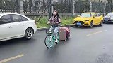 女子用共享单车搬家，身上背满了包