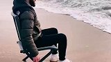 男子看见海浪来袭，直接把脚抬起