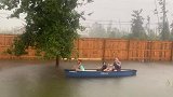 美国：佛罗里达州一名父亲带着子女在被暴雨淹没的后院划船