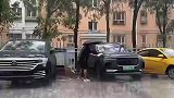 车主趁着下雨天，手撑雨伞给车洗澡