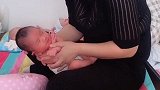专业月嫂教宝宝趴着睡觉，宝宝好像很不满意，大声朝月嫂叫了一声