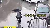 下雨天学生打伞骑行视野受限，撞上正在倒车的小轿车