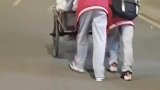 老人蹬三轮车艰难爬坡。几名初中生主动帮忙推车