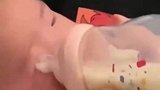 妈妈边辅导大宝作业边用奶瓶喂二宝喝奶