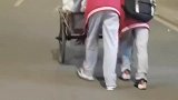 老人蹬三轮车艰难爬坡。几名初中生主动帮忙推车
